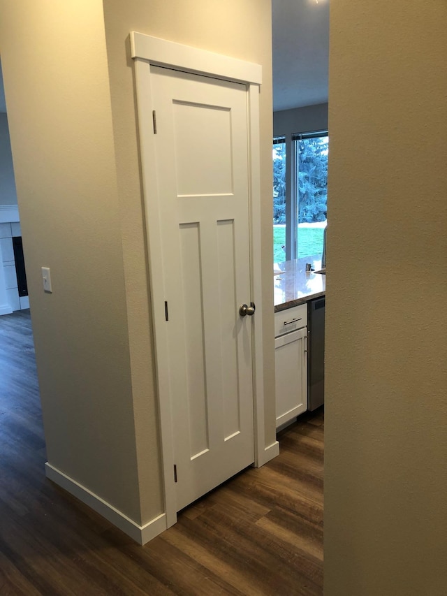 corridor featuring baseboards and dark wood-style flooring