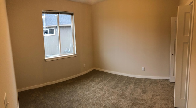 unfurnished room featuring baseboards and dark colored carpet