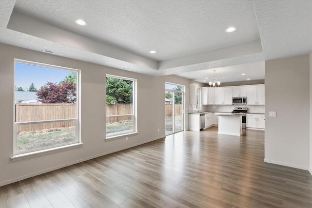 503 N Arc Ct, Spokane Valley, WA 99016 - unfurnished living room featuring a tray ceiling, a chandelier, wood finished floors, recessed lighting, and a textured ceiling