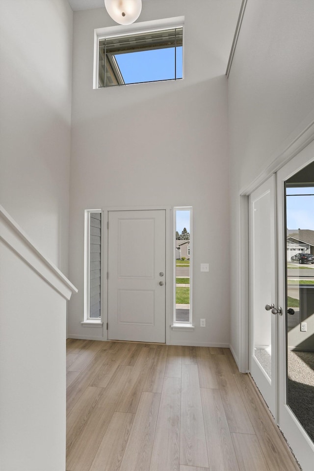 entryway with a high ceiling, light wood-style flooring, and plenty of natural light