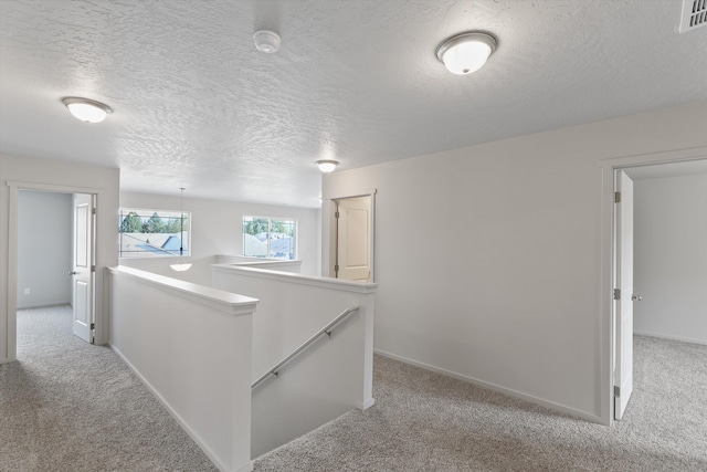 hall featuring baseboards, an upstairs landing, and light colored carpet