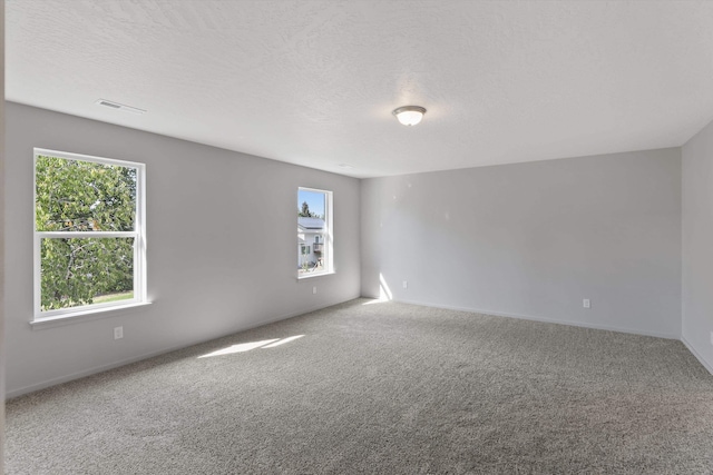 carpeted spare room with visible vents and a textured ceiling