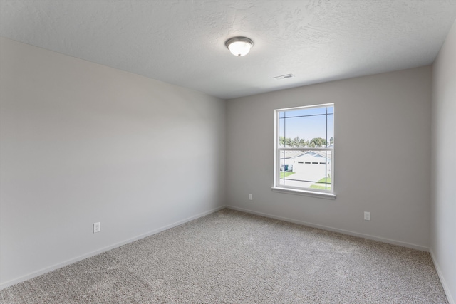 spare room with carpet flooring, a textured ceiling, and visible vents
