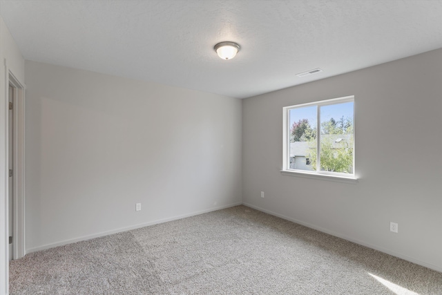carpeted empty room featuring baseboards, a textured ceiling, and visible vents