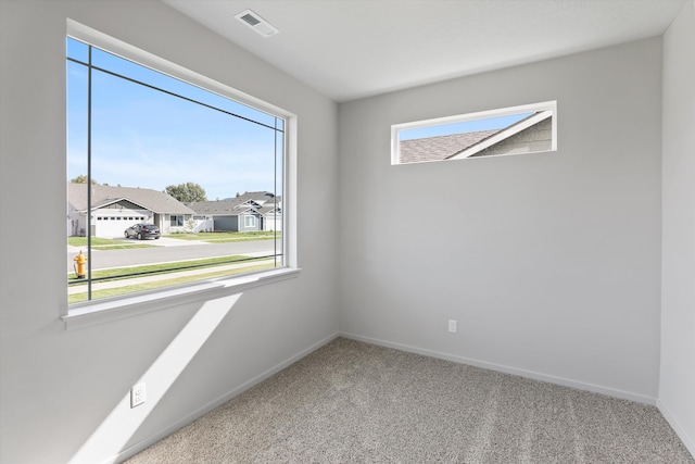empty room featuring baseboards, visible vents, carpet floors, and a residential view