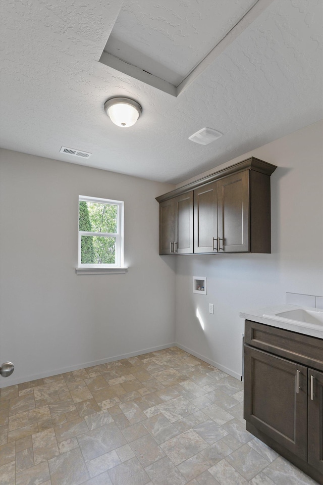 laundry room with a textured ceiling, baseboards, visible vents, cabinet space, and hookup for a washing machine