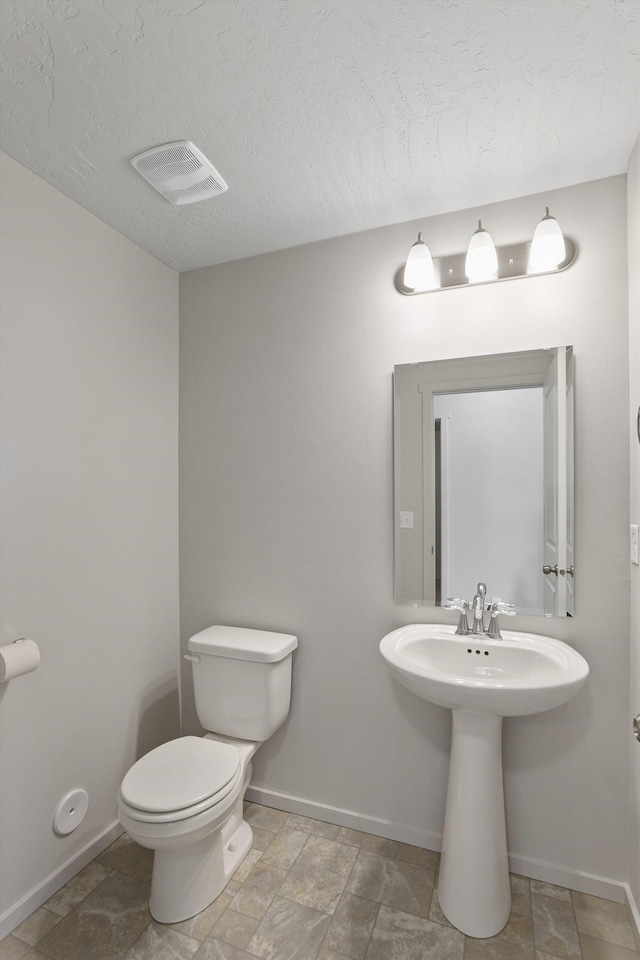 bathroom featuring toilet, baseboards, and visible vents