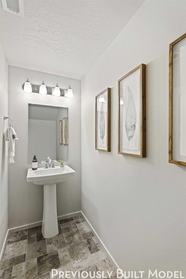 509 N Arc Ct, Spokane Valley, WA 99016 - bathroom with stone finish floor, a textured ceiling, baseboards, and visible vents