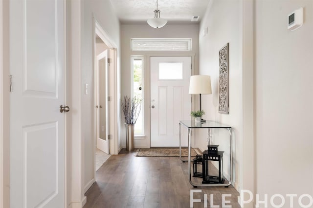 foyer entrance with baseboards, visible vents, and wood finished floors