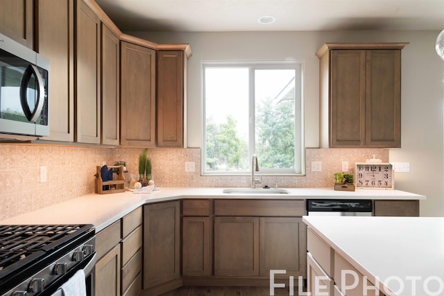 kitchen featuring light countertops, stainless steel microwave, tasteful backsplash, a sink, and dishwashing machine
