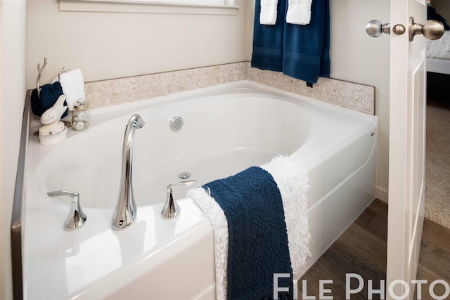 bathroom with wood finished floors and a bath