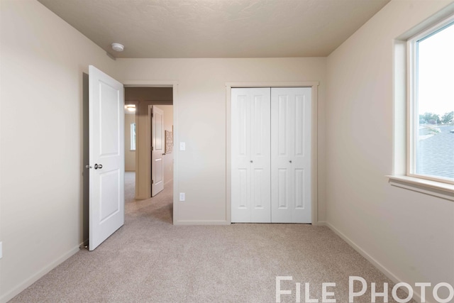 unfurnished bedroom with carpet floors, baseboards, and a closet
