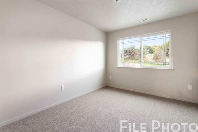 carpeted spare room featuring baseboards and visible vents