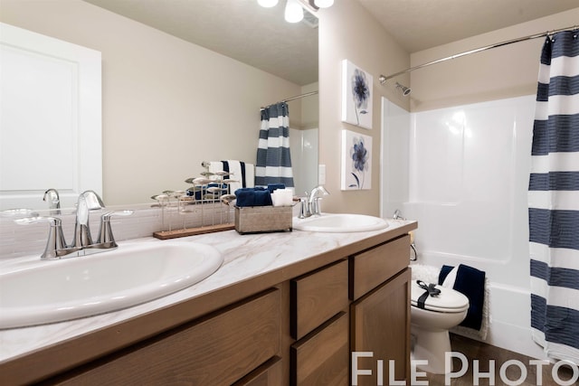 full bath with double vanity, shower / bathtub combination with curtain, a sink, and toilet