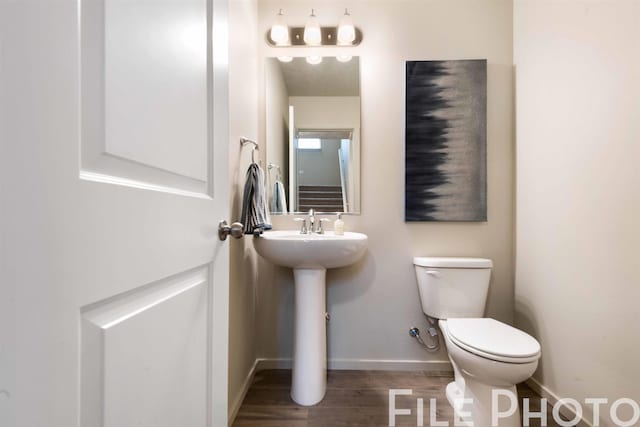 bathroom with baseboards, toilet, and wood finished floors