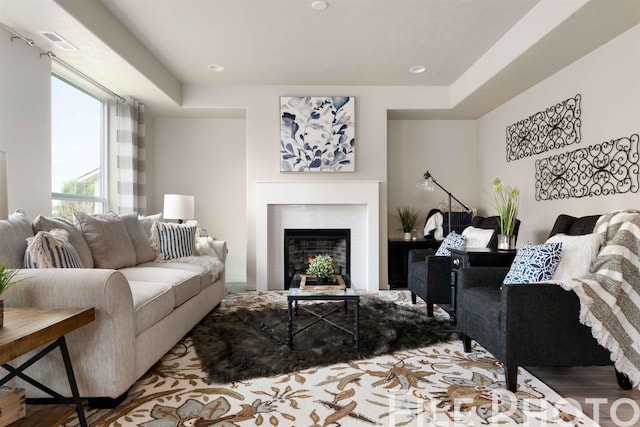living area with wood finished floors, a lit fireplace, and visible vents