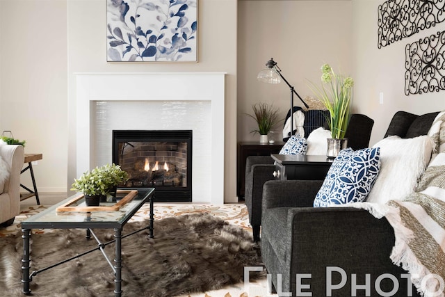 living area featuring baseboards and a lit fireplace