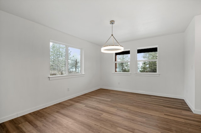 unfurnished room featuring a wealth of natural light, wood finished floors, and baseboards