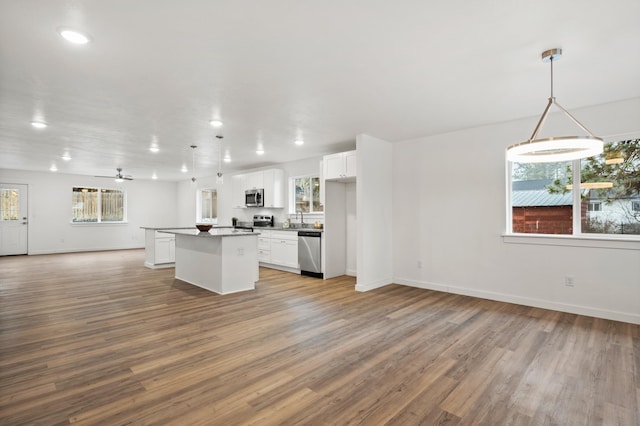 kitchen featuring a sink, a kitchen island, open floor plan, light wood-style flooring, and stainless steel appliances