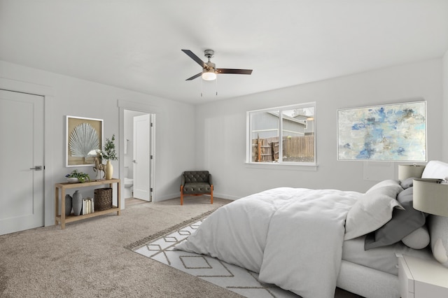 carpeted bedroom with baseboards, ceiling fan, and ensuite bath