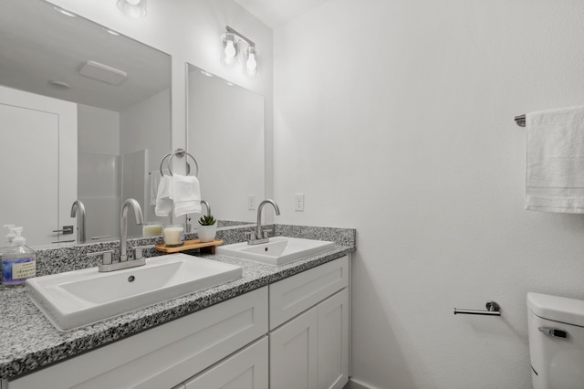 bathroom with double vanity, a sink, and toilet