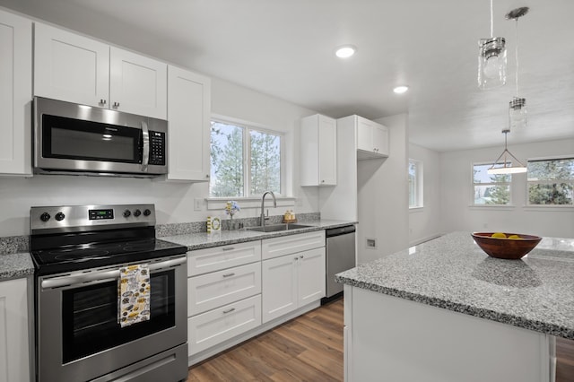 kitchen featuring light stone counters, a sink, white cabinetry, stainless steel appliances, and dark wood-type flooring