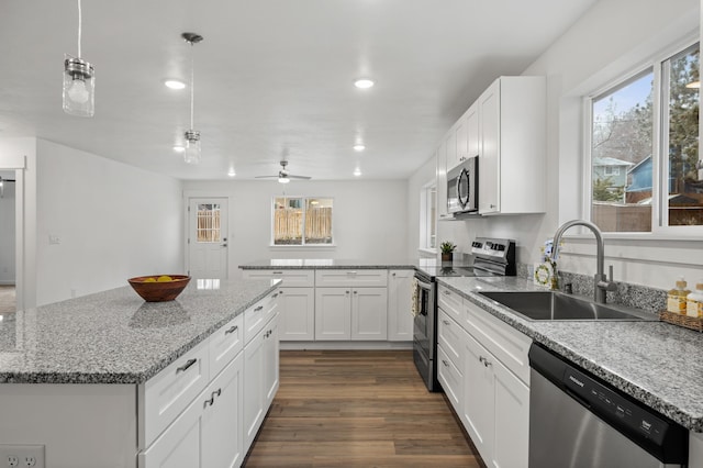 kitchen featuring dark wood-style flooring, a peninsula, appliances with stainless steel finishes, white cabinetry, and a sink