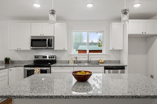 kitchen with recessed lighting, stainless steel appliances, a kitchen island, a sink, and white cabinets
