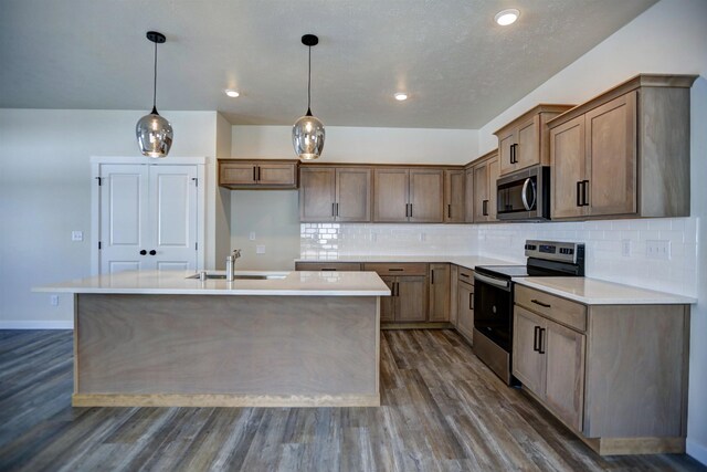 18517 E Michielli Ln, Spokane Valley, WA 99016 - kitchen featuring appliances with stainless steel finishes, a sink, dark wood finished floors, a kitchen island with sink, and tasteful backsplash