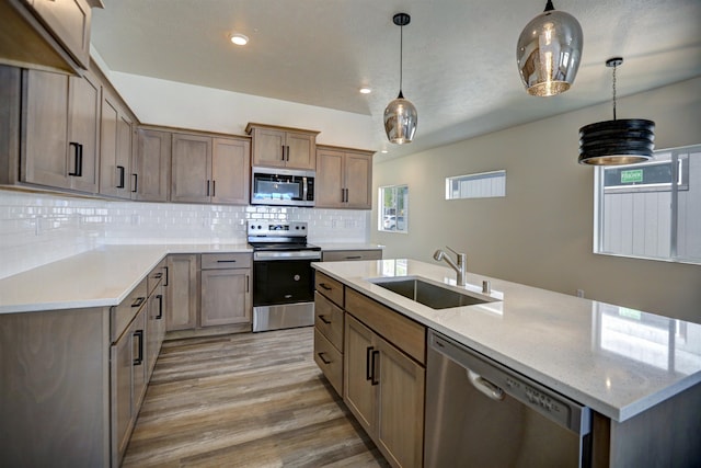 18517 E Michielli Ln, Spokane Valley, WA 99016 - kitchen featuring stainless steel appliances, a sink, light wood-style flooring, backsplash, and an island with sink