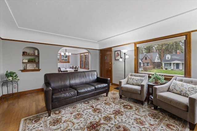 127 W 25th Ave, Spokane, WA 99203 - living area featuring baseboards, built in shelves, wood finished floors, arched walkways, and a notable chandelier