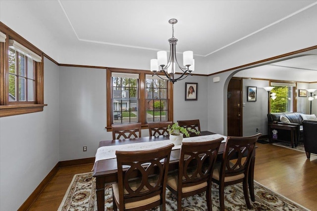 127 W 25th Ave, Spokane, WA 99203 - dining area featuring baseboards, a notable chandelier, arched walkways, and dark wood-type flooring