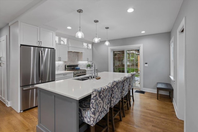 127 W 25th Ave, Spokane, WA 99203 - kitchen with stainless steel appliances, premium range hood, a center island with sink, a sink, and backsplash