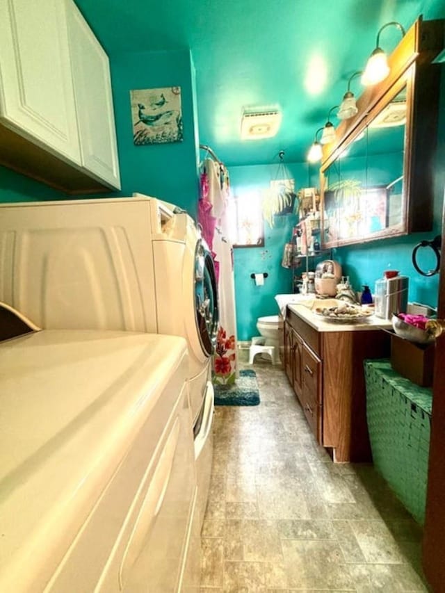 bathroom with stone finish floor, toilet, curtained shower, vanity, and washer and dryer