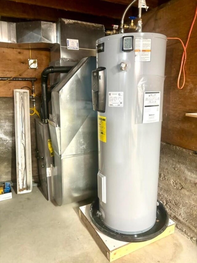 utility room with heating unit and electric water heater