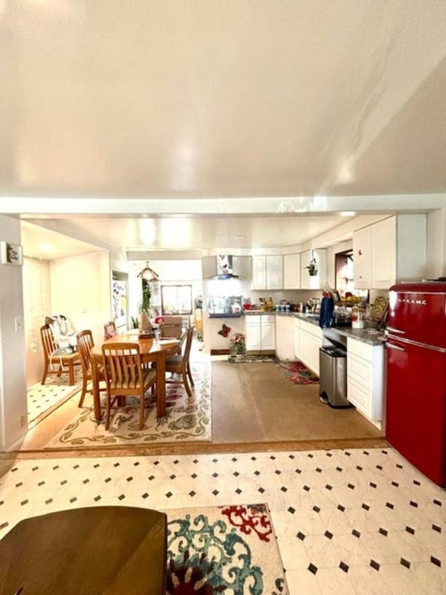 kitchen featuring wall chimney exhaust hood, white cabinets, dark countertops, and fridge