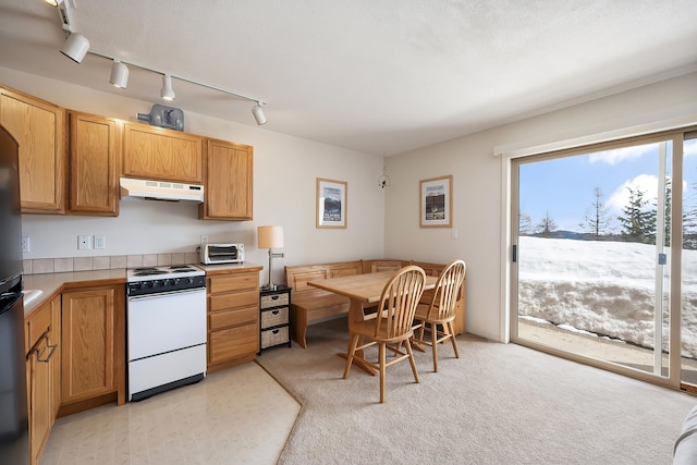kitchen featuring white range with electric stovetop, tile countertops, a toaster, and under cabinet range hood