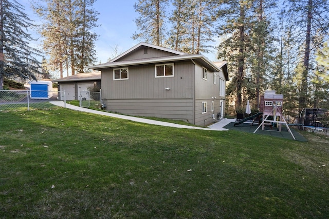 view of home's exterior featuring a trampoline, a garage, a yard, fence, and a playground