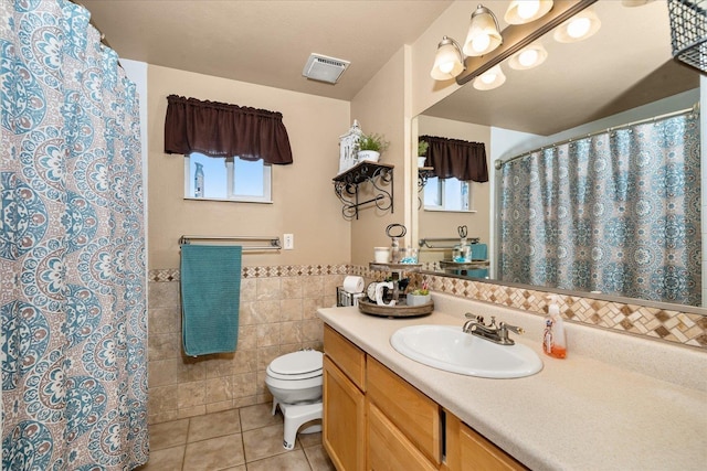bathroom featuring vanity, tile patterned flooring, visible vents, toilet, and tile walls