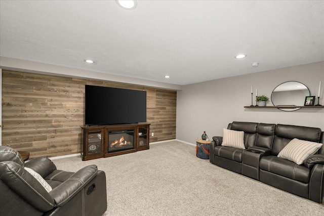 carpeted living room with wooden walls, baseboards, a glass covered fireplace, and recessed lighting