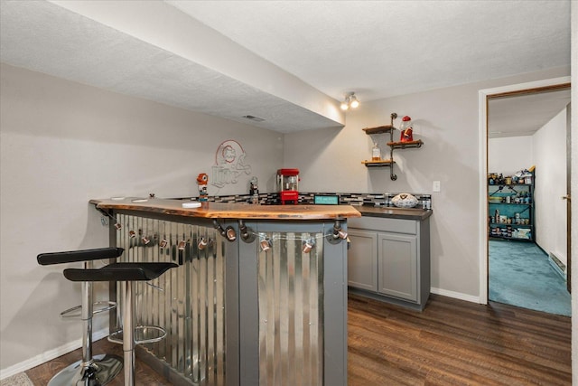 bar featuring dark wood-type flooring, visible vents, baseboards, and a dry bar