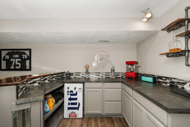 kitchen with dark wood-style floors, open shelves, dark countertops, visible vents, and decorative backsplash