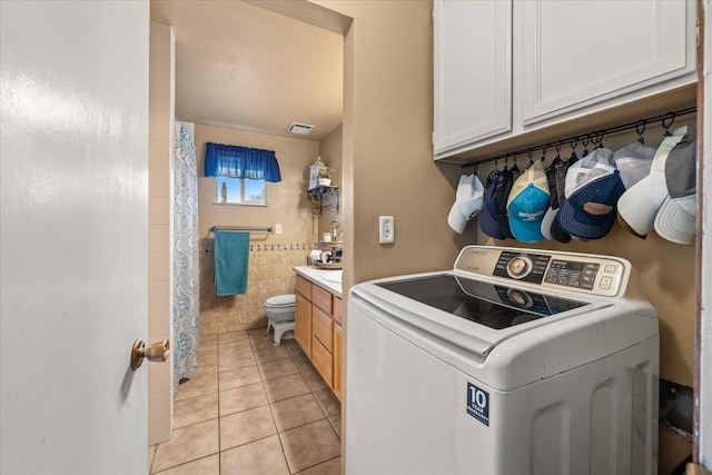 clothes washing area featuring tile walls, laundry area, light tile patterned floors, and washer / dryer