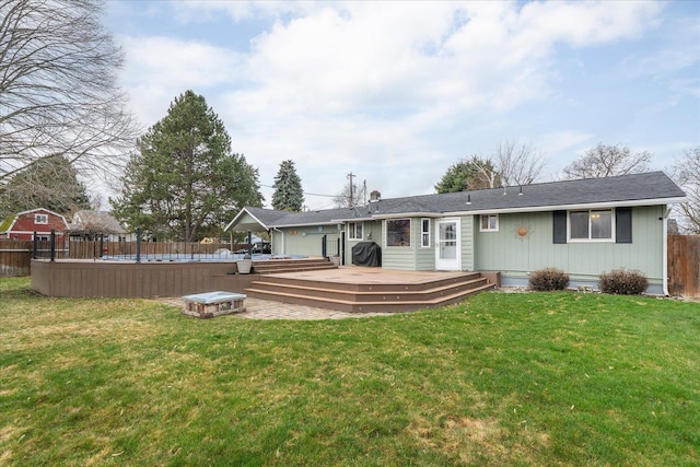 rear view of property featuring fence, a deck, a lawn, and a fenced in pool