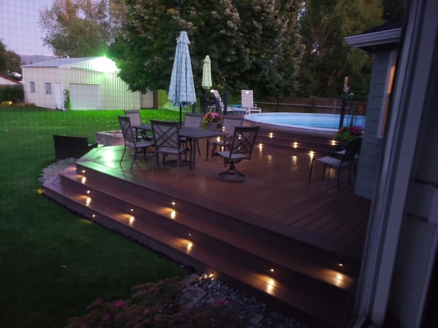 wooden terrace featuring a lawn, an outdoor structure, a fenced in pool, and outdoor dining area