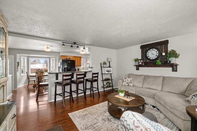 living room featuring a textured ceiling, baseboards, and dark wood finished floors