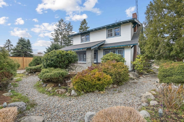 view of front of house featuring fence, a shingled roof, and a chimney