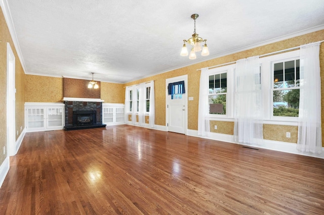 unfurnished living room with a notable chandelier, visible vents, crown molding, and wood finished floors