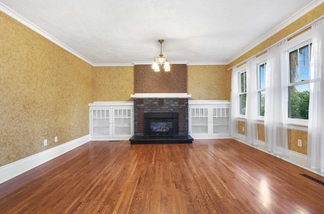unfurnished living room featuring ornamental molding, visible vents, wood finished floors, a brick fireplace, and wallpapered walls