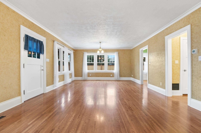 unfurnished room featuring a chandelier, visible vents, crown molding, and wood finished floors